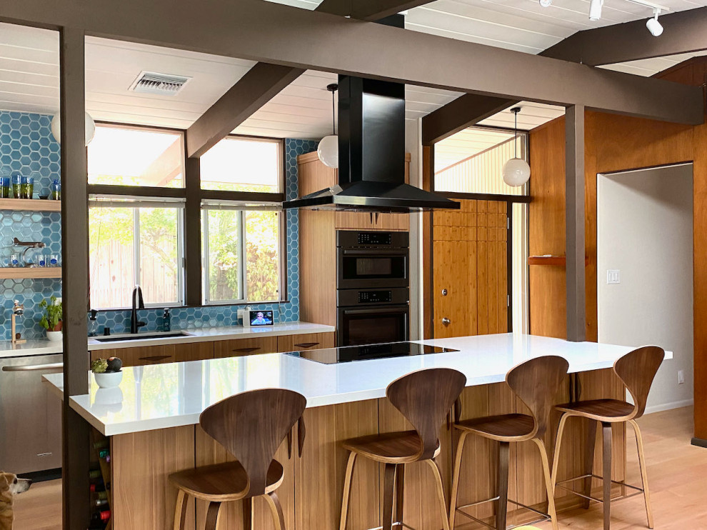 Inspiration for a large 1960s light wood floor, yellow floor and exposed beam open concept kitchen remodel in San Francisco with a double-bowl sink, flat-panel cabinets, medium tone wood cabinets, quartz countertops, blue backsplash, ceramic backsplash, black appliances, an island and white countertops