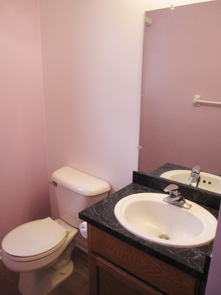 Design ideas for a small traditional bathroom in Detroit with recessed-panel cabinets, brown cabinets, a two-piece toilet, pink walls, dark hardwood floors, a drop-in sink, laminate benchtops, brown floor, white benchtops, a single vanity and a freestanding vanity.