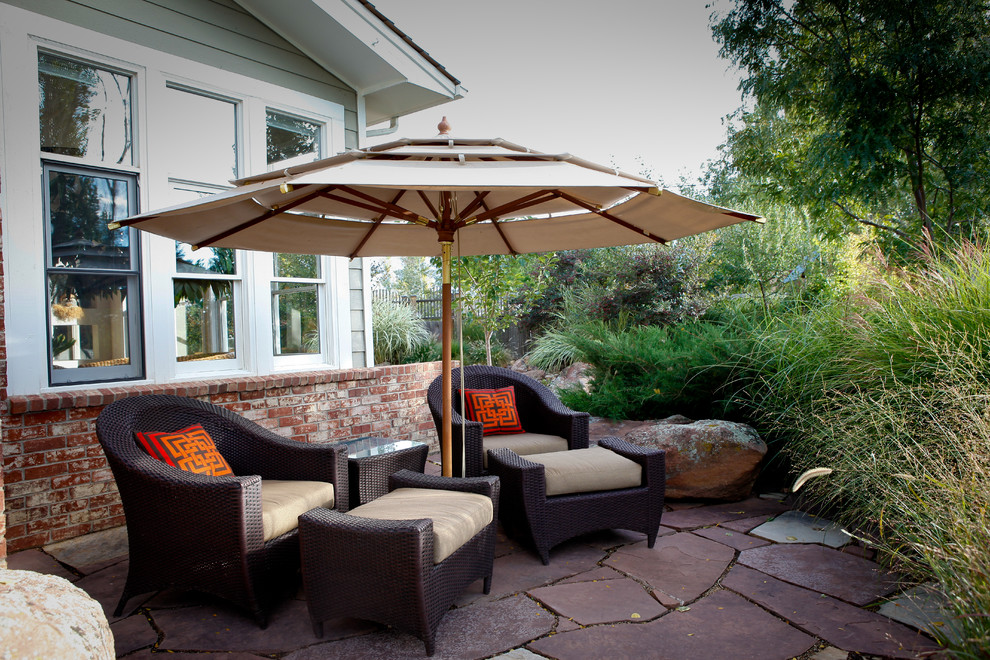 This is an example of a mid-sized traditional backyard patio in Denver with natural stone pavers.