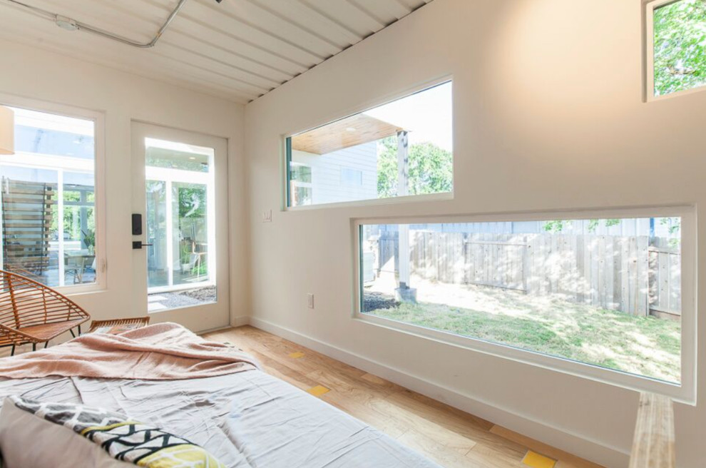 Photo of a small industrial guest bedroom in Austin with white walls and light hardwood floors.