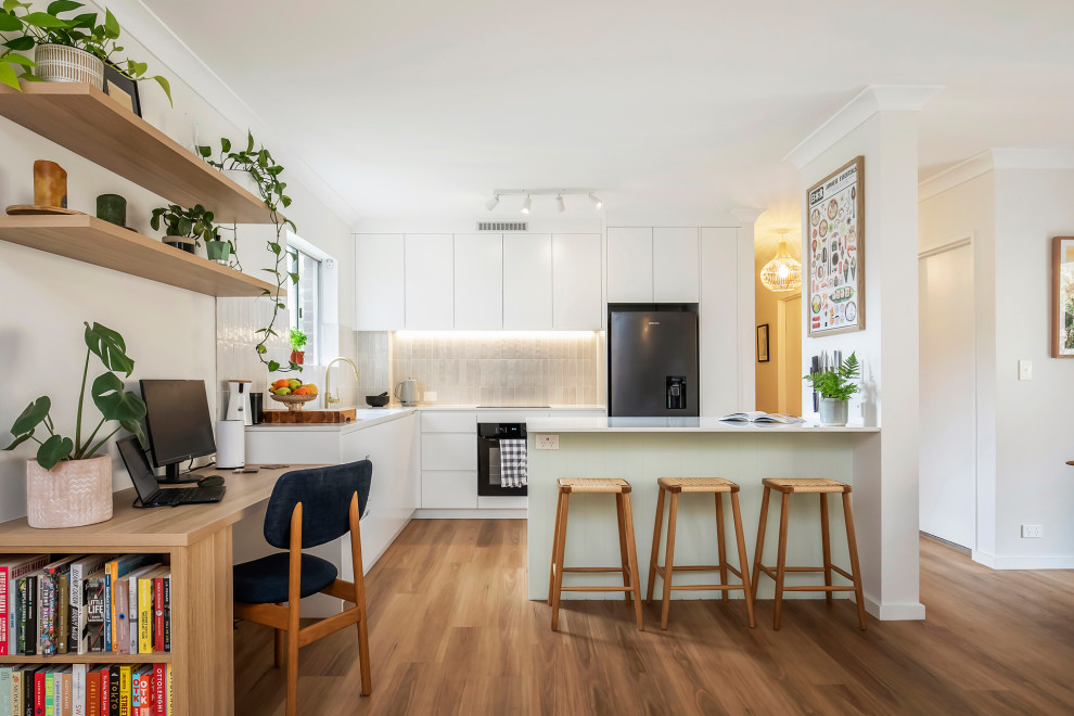 Design ideas for a small modern l-shaped open plan kitchen in Sydney with an undermount sink, flat-panel cabinets, white cabinets, quartz benchtops, white splashback, ceramic splashback, stainless steel appliances, medium hardwood floors, with island, brown floor and white benchtop.