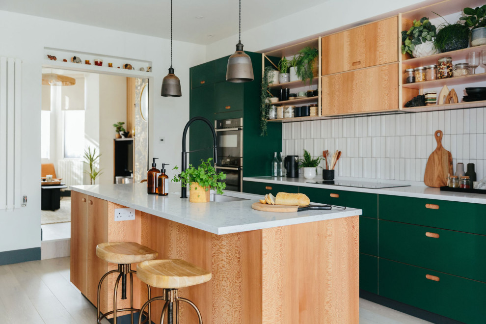 Foto på ett mellanstort kök med öppen planlösning, med en integrerad diskho, släta luckor, gröna skåp, vitt stänkskydd, stänkskydd i keramik, färgglada vitvaror, laminatgolv, en köksö och grått golv