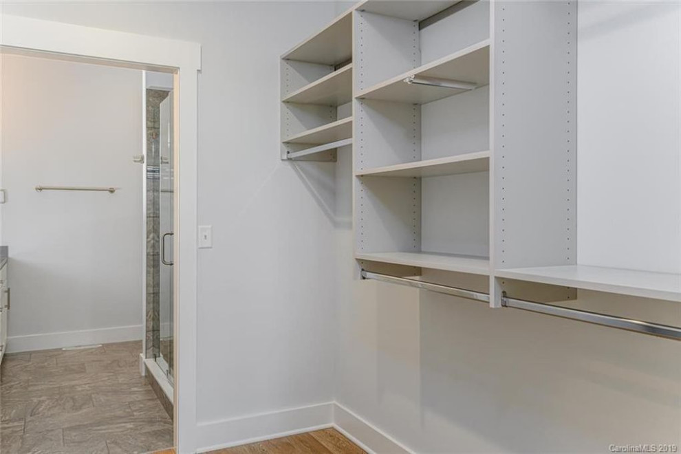 Design ideas for a mid-sized transitional gender-neutral walk-in wardrobe in Other with grey cabinets, vinyl floors and brown floor.