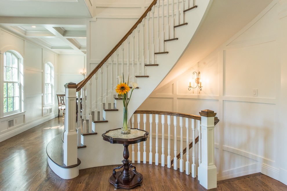 Traditional wood curved staircase in New York with painted wood risers and wood railing.