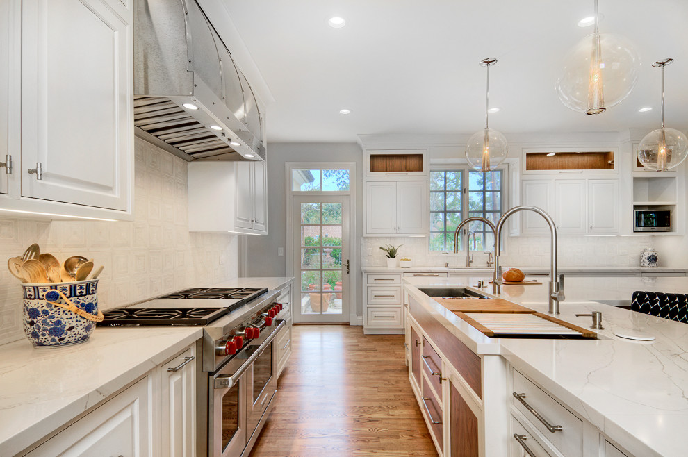 Large transitional l-shaped open plan kitchen in San Francisco with an undermount sink, beaded inset cabinets, white cabinets, quartz benchtops, white splashback, stone tile splashback, panelled appliances, light hardwood floors, with island, beige floor and white benchtop.