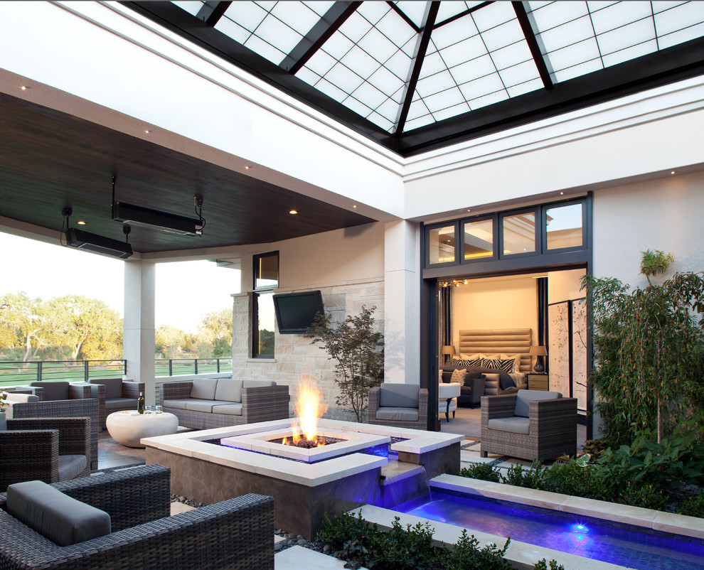 Photo of a large transitional courtyard patio in Denver with a fire feature, natural stone pavers and an awning.