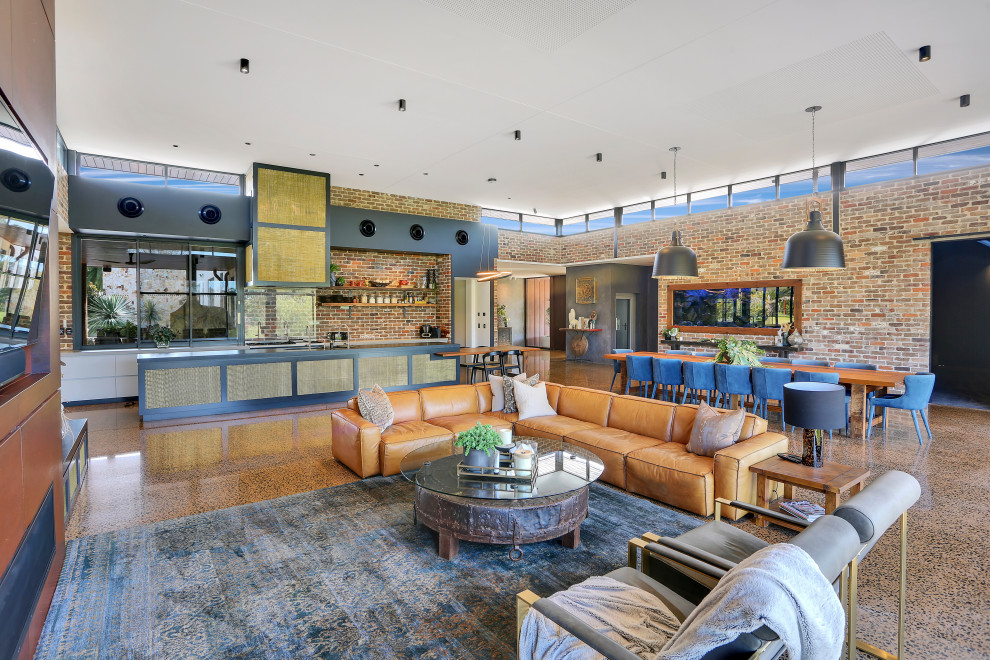 На фото: огромная открытая гостиная комната в стиле лофт с бетонным полом, коричневым полом, коричневыми стенами, стандартным камином, фасадом камина из металла и телевизором на стене