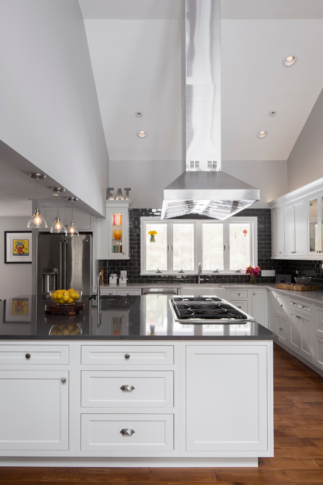Design ideas for a large contemporary l-shaped open plan kitchen in Boston with a farmhouse sink, recessed-panel cabinets, white cabinets, quartz benchtops, black splashback, subway tile splashback, stainless steel appliances, medium hardwood floors and with island.