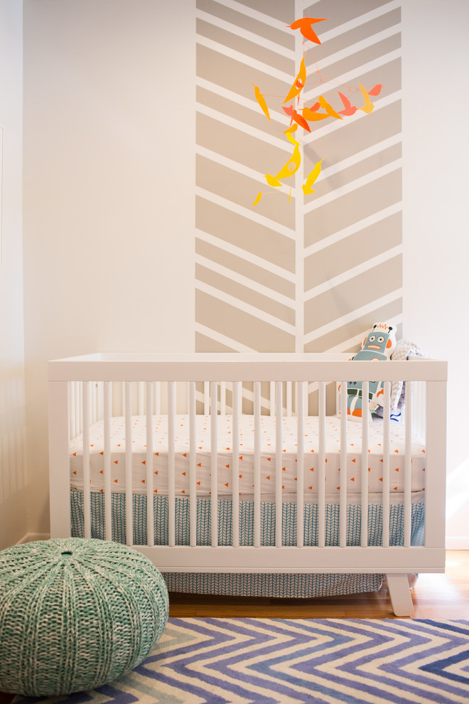 This is an example of a mid-sized nursery for boys in Orange County with white walls and light hardwood floors.