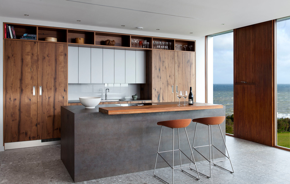 This is an example of a mid-sized contemporary single-wall open plan kitchen in Belfast with a farmhouse sink, flat-panel cabinets, dark wood cabinets, panelled appliances and with island.
