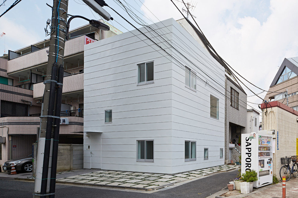 Contemporary split-level white house exterior in Tokyo with metal siding and a flat roof.