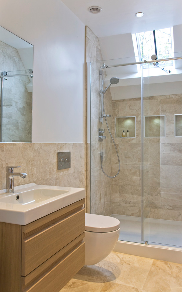 Transitional 3/4 bathroom in Gloucestershire with a console sink, flat-panel cabinets, light wood cabinets, a wall-mount toilet, beige tile, white walls and an alcove shower.