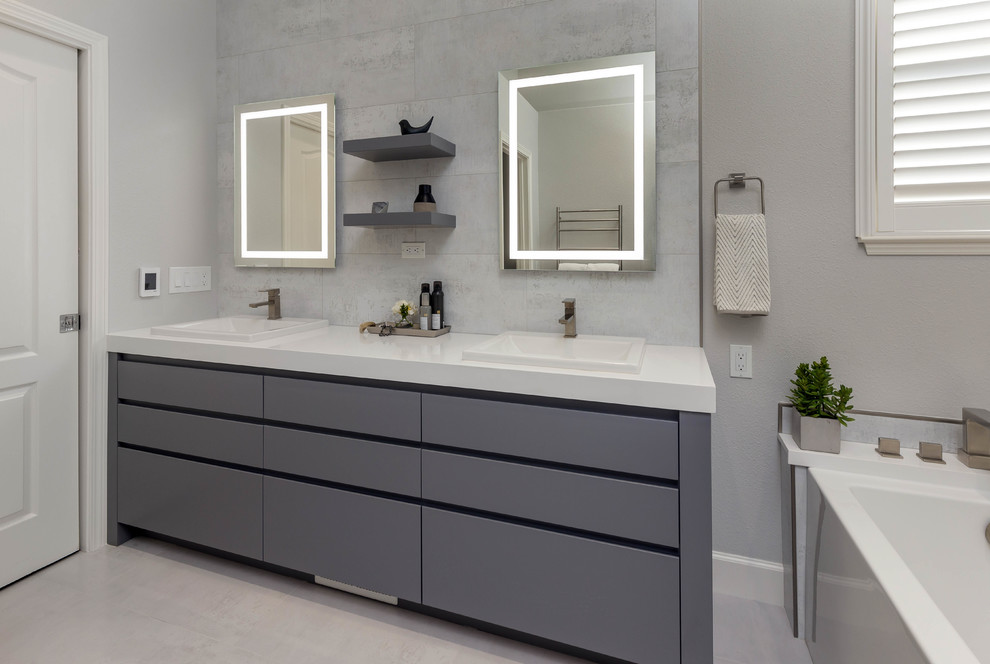 Design ideas for a large contemporary master bathroom in San Francisco with flat-panel cabinets, grey cabinets, gray tile, porcelain tile, grey walls, porcelain floors, granite benchtops, white floor, white benchtops, an alcove tub and a drop-in sink.