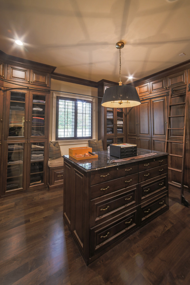 Design ideas for an expansive traditional men's dressing room in Charlotte with raised-panel cabinets, dark wood cabinets and dark hardwood floors.