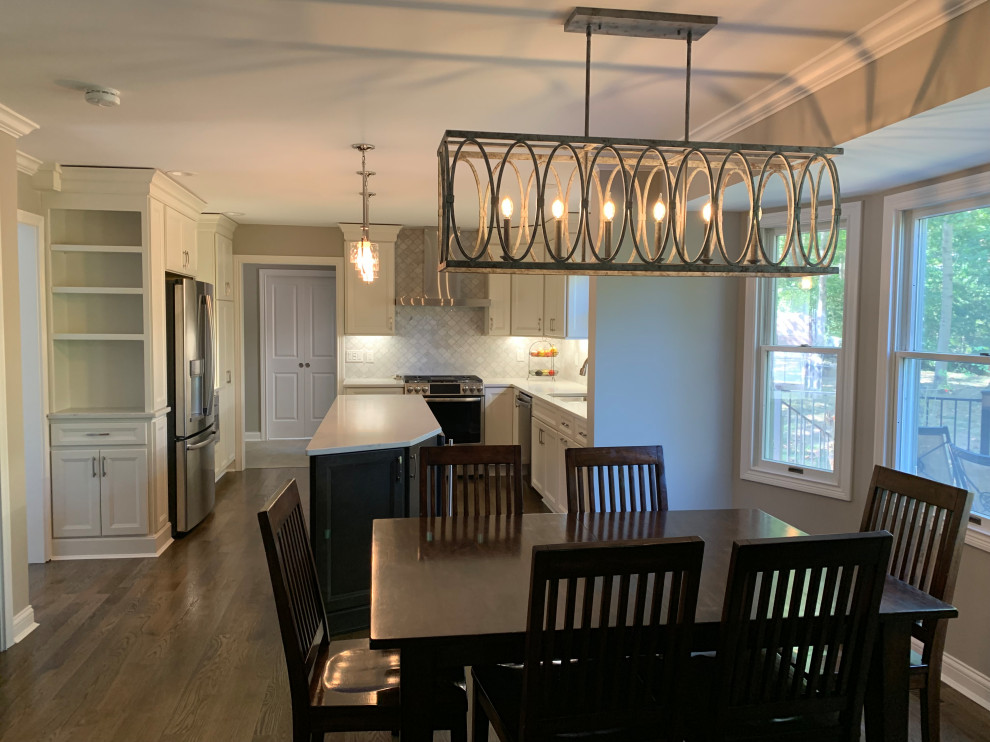 Inspiration for a mid-sized transitional l-shaped medium tone wood floor and brown floor eat-in kitchen remodel in Cincinnati with an undermount sink, flat-panel cabinets, white cabinets, quartz countertops, white backsplash, marble backsplash, stainless steel appliances, an island and white countertops