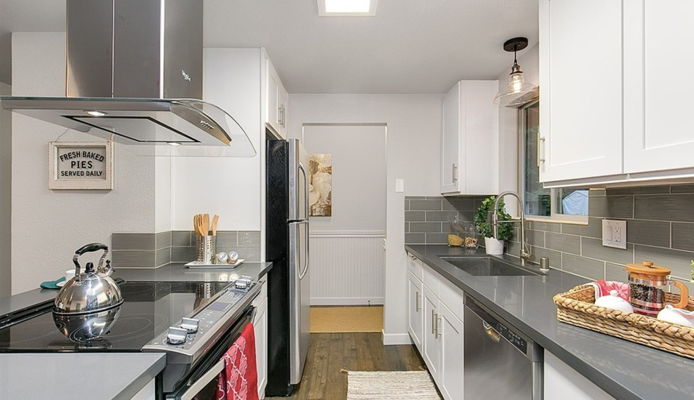 Inspiration for a small transitional galley dark wood floor open concept kitchen remodel in Seattle with an undermount sink, recessed-panel cabinets, white cabinets, concrete countertops, gray backsplash, glass tile backsplash, stainless steel appliances and a peninsula