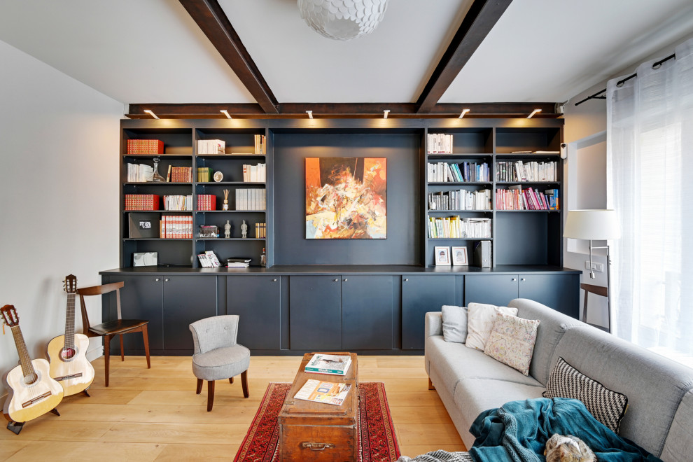 На фото: открытая гостиная комната:: освещение в современном стиле с с книжными шкафами и полками, черными стенами, светлым паркетным полом и балками на потолке с