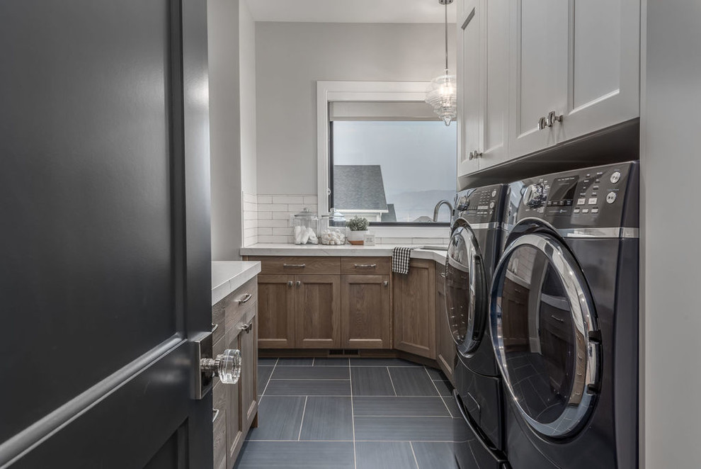 This is an example of a mid-sized transitional galley utility room in Salt Lake City with an undermount sink, recessed-panel cabinets, brown cabinets, quartzite benchtops, grey walls, ceramic floors, a side-by-side washer and dryer, blue floor and white benchtop.