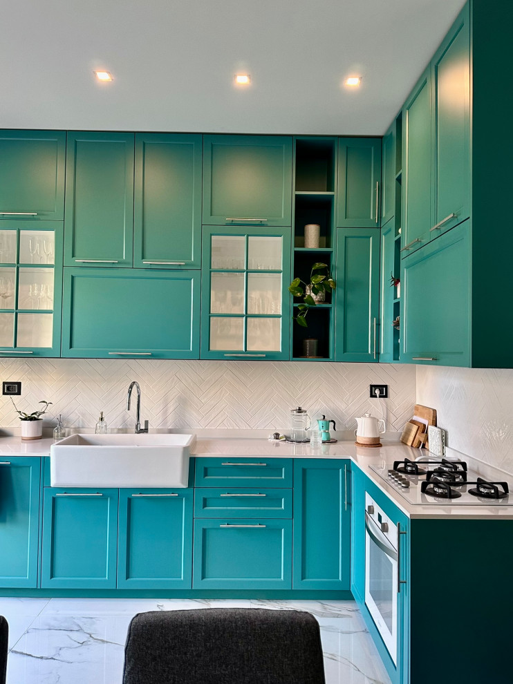 Design ideas for a mid-sized contemporary l-shaped eat-in kitchen in Milan with a farmhouse sink, raised-panel cabinets, turquoise cabinets, quartz benchtops, white splashback, porcelain splashback, white appliances, porcelain floors, no island, white floor and white benchtop.