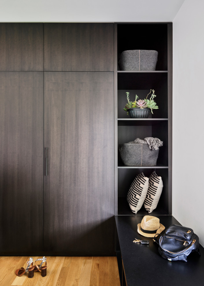 Modelo de armario y vestidor moderno de tamaño medio con a medida, armarios con paneles lisos, puertas de armario de madera en tonos medios y suelo de madera clara