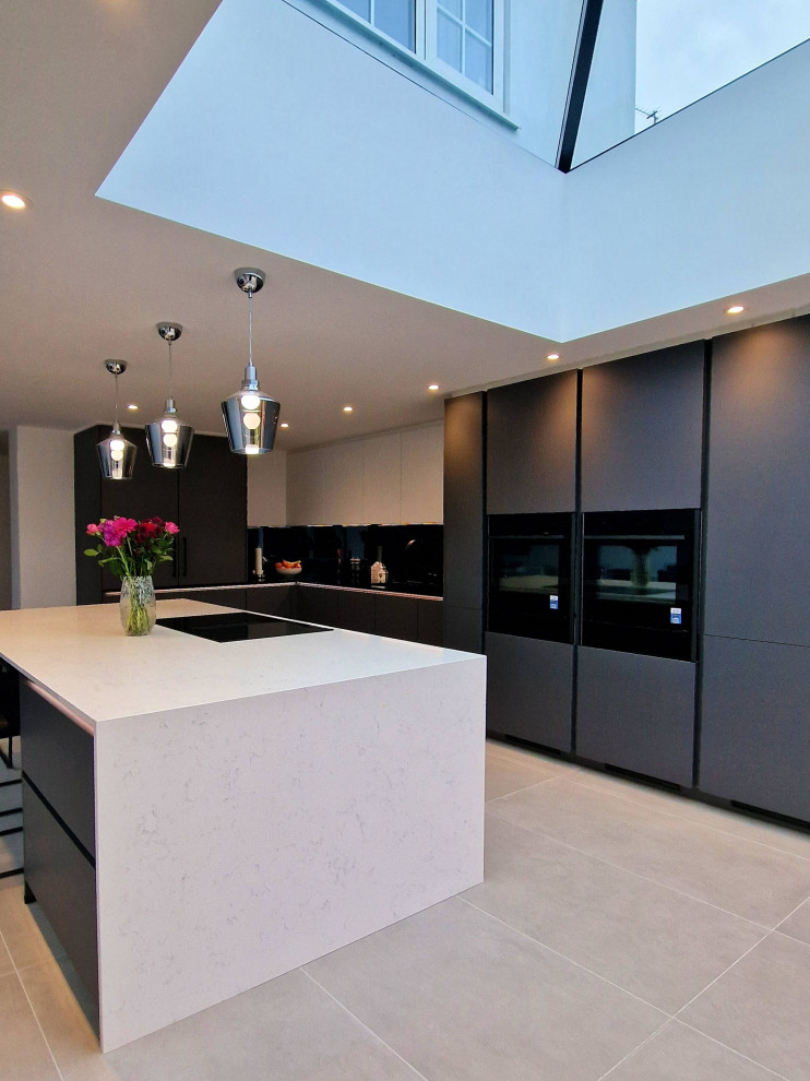 Medium sized contemporary l-shaped kitchen/diner in Hertfordshire with a single-bowl sink, flat-panel cabinets, grey cabinets, quartz worktops, black splashback, integrated appliances, an island, beige floors and beige worktops.