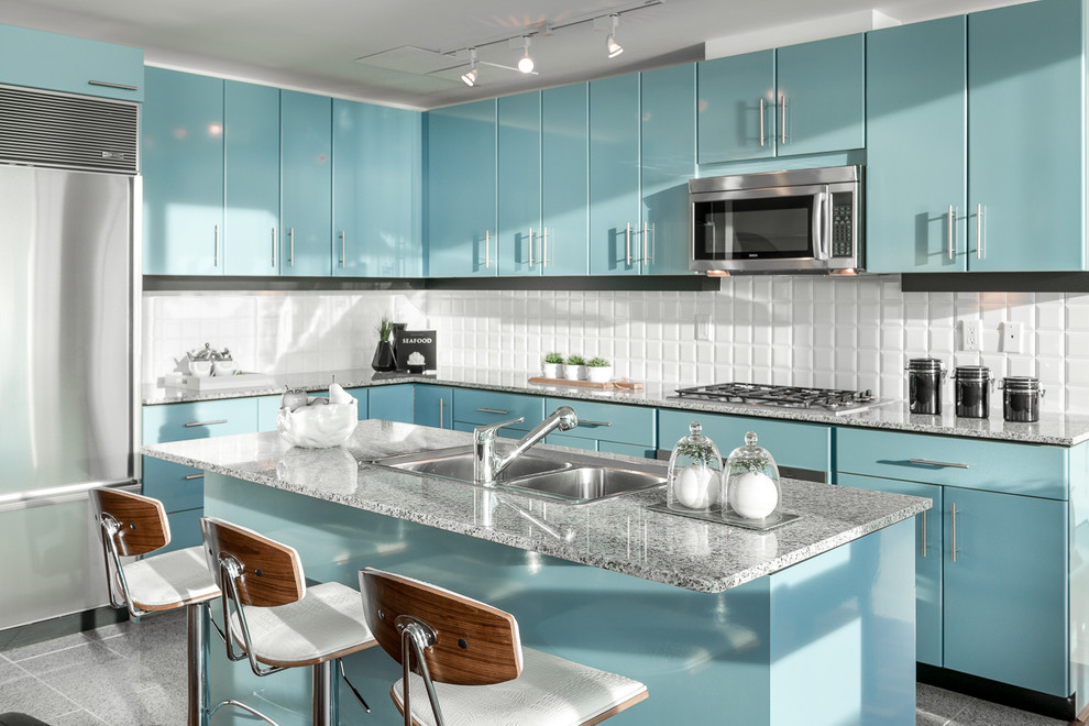 Contemporary u-shaped kitchen in Vancouver with a double-bowl sink, flat-panel cabinets, blue cabinets, white splashback, stainless steel appliances and with island.