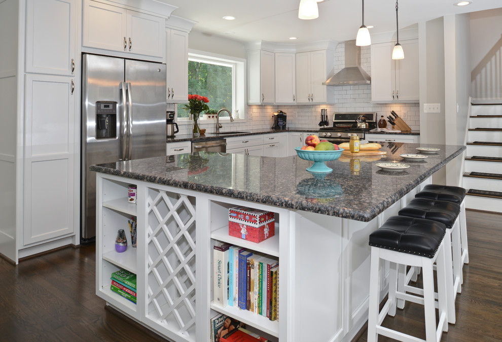 Mid-sized modern l-shaped eat-in kitchen in DC Metro with flat-panel cabinets, white cabinets, zinc benchtops, white splashback, stainless steel appliances, with island, brown floor and black benchtop.
