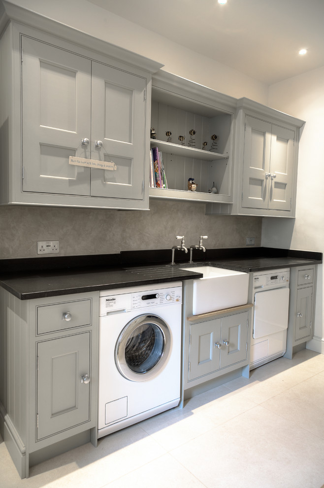 Mid-sized traditional laundry room in Hampshire with a farmhouse sink, flat-panel cabinets, grey cabinets, granite benchtops, limestone floors and a side-by-side washer and dryer.