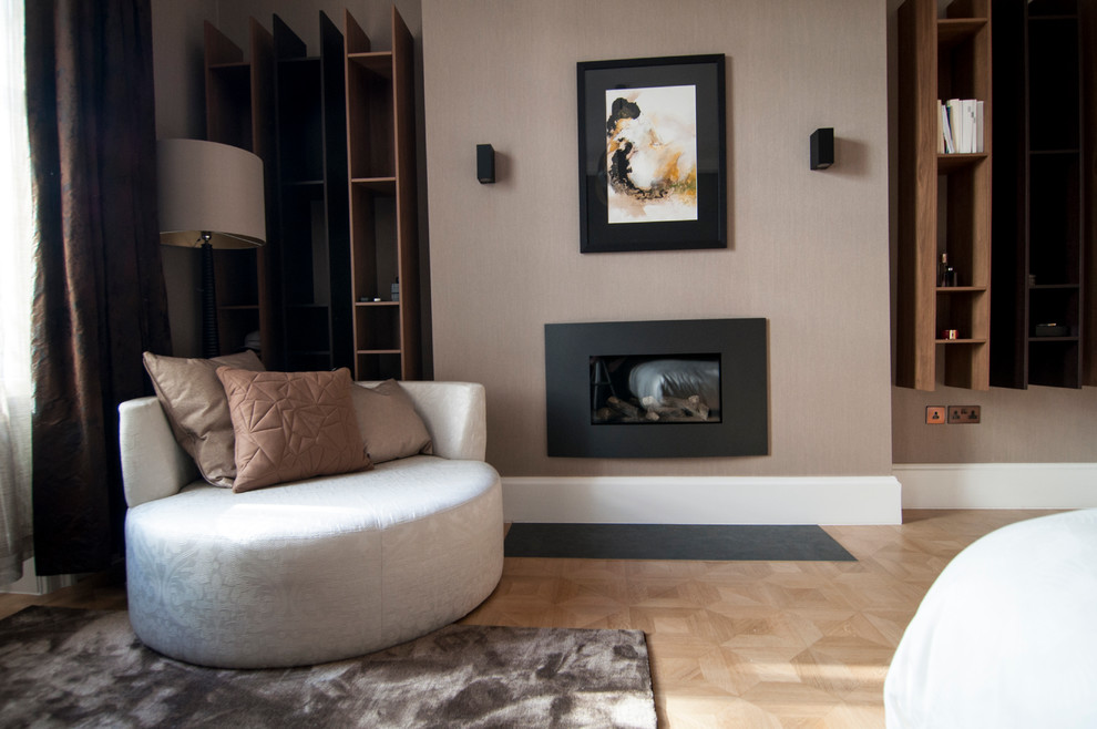 Design ideas for a mid-sized contemporary master bedroom in London with brown walls, medium hardwood floors, a standard fireplace and a metal fireplace surround.