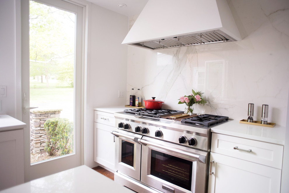 Enclosed kitchen - transitional dark wood floor and brown floor enclosed kitchen idea with an undermount sink, shaker cabinets, white cabinets, quartz countertops, white backsplash, stone slab backsplash, stainless steel appliances and an island