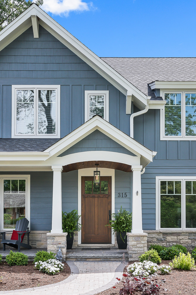 Inspiration for a large arts and crafts two-storey blue house exterior in Chicago with a gable roof, a shingle roof, wood siding, board and batten siding and clapboard siding.