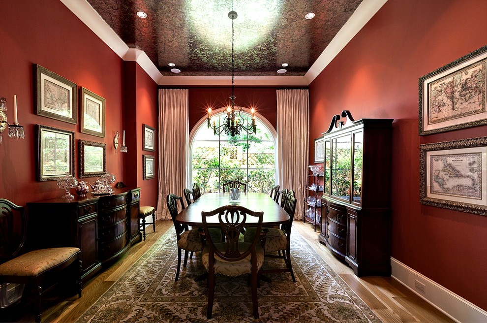 This is an example of a large traditional separate dining room in Austin with red walls, light hardwood floors and no fireplace.