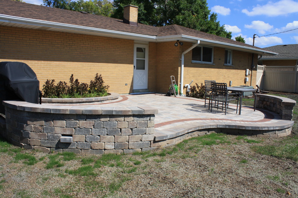This is an example of a contemporary full sun garden for summer in Chicago with a retaining wall and concrete pavers.