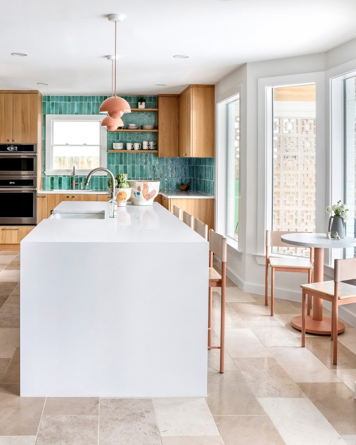 This is an example of a small modern l-shaped eat-in kitchen in Austin with a drop-in sink, flat-panel cabinets, medium wood cabinets, glass benchtops, blue splashback, ceramic splashback, panelled appliances, light hardwood floors, with island, brown floor, white benchtop and recessed.