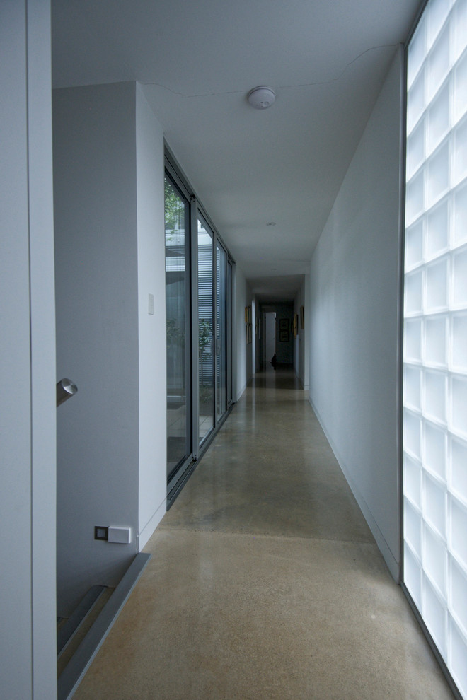 Inspiration for a mid-sized hallway in Adelaide with white walls and concrete floors.
