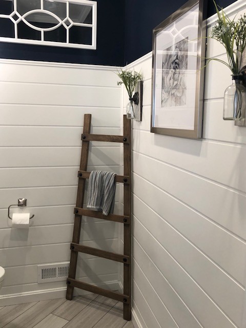 Example of a mid-sized transitional 3/4 porcelain floor and beige floor bathroom design in DC Metro with recessed-panel cabinets, black cabinets, a two-piece toilet, blue walls, an undermount sink, engineered quartz countertops and white countertops