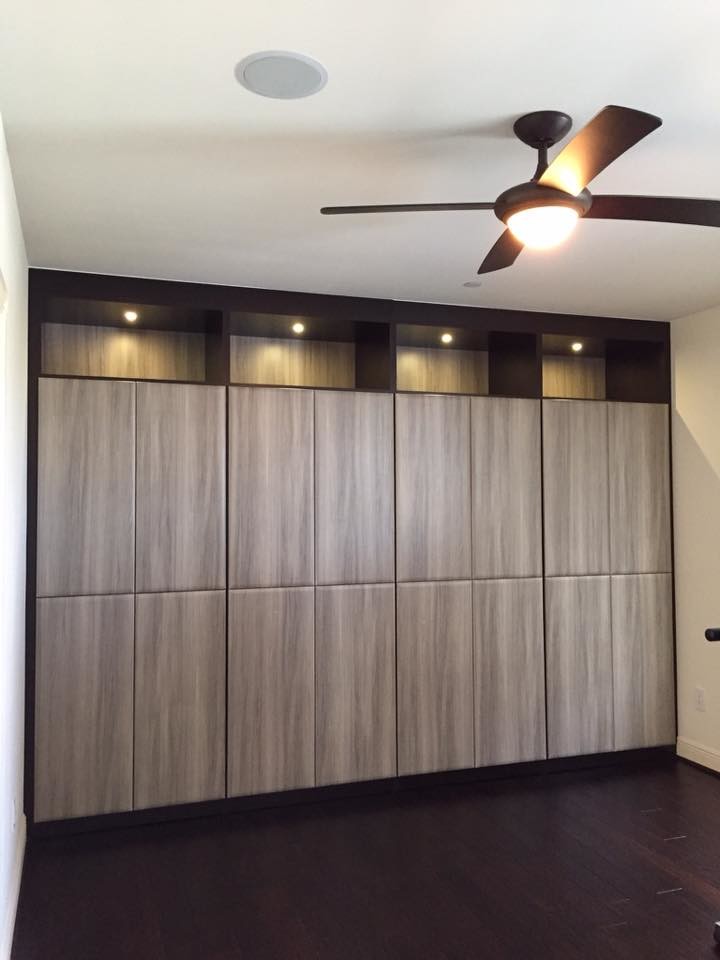 This is an example of a mid-sized contemporary gender-neutral walk-in wardrobe in Miami with flat-panel cabinets, brown cabinets and brown floor.