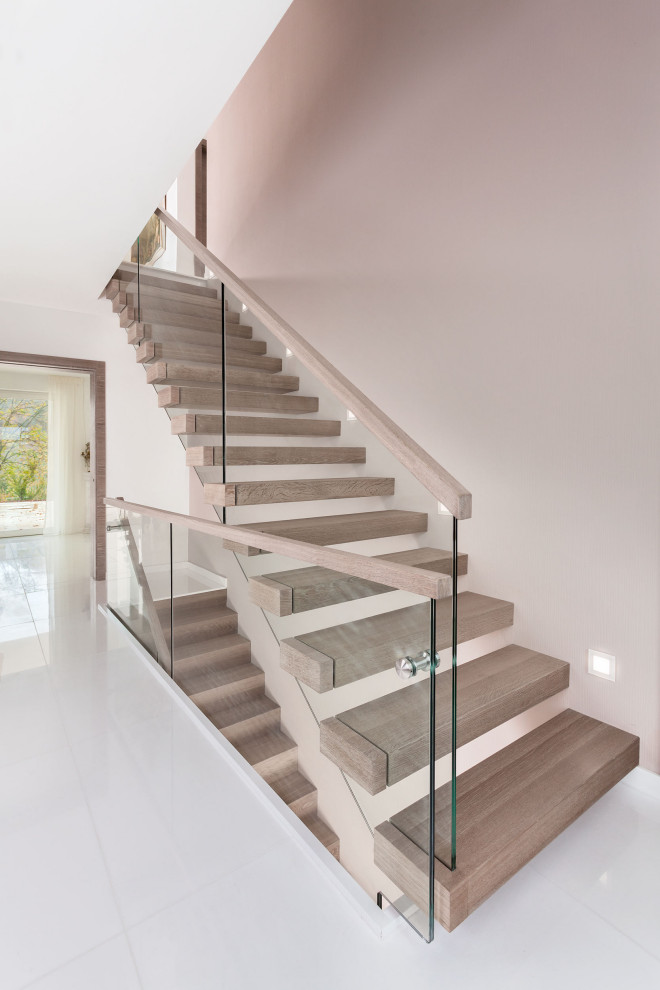 Свежая идея для дизайна: прямая лестница в современном стиле с деревянными ступенями и стеклянными перилами без подступенок - отличное фото интерьера