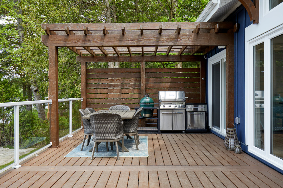 This is an example of a mid-sized country backyard and ground level deck in Toronto with with dock, a pergola and glass railing.
