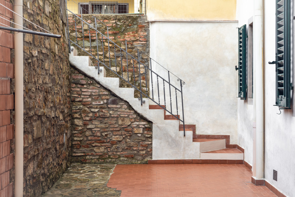 На фото: маленькая угловая бетонная лестница в стиле рустика с ступенями из плитки и металлическими перилами для на участке и в саду с
