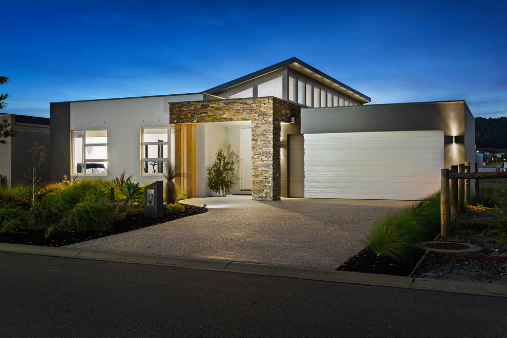 Photo of a large contemporary two-storey brick grey house exterior in Melbourne with a flat roof and a metal roof.