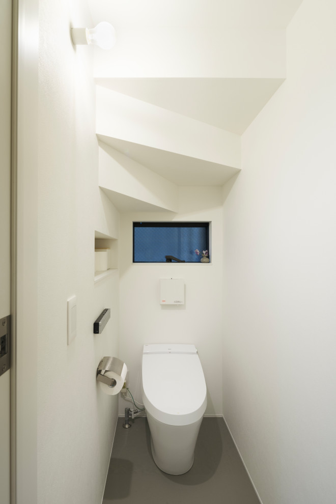 Exempel på ett litet minimalistiskt toalett, med en toalettstol med hel cisternkåpa, vita väggar, linoleumgolv och grått golv