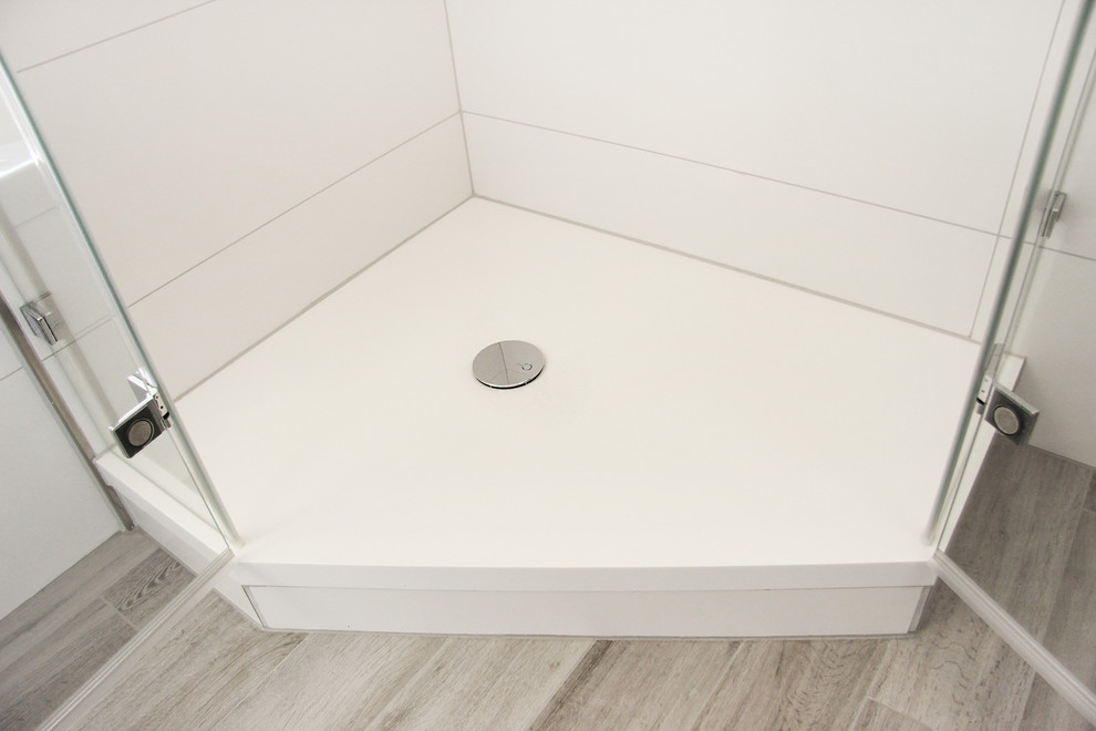Badezimmer With Eckbadewanne, Eckdusche, Wandtoilette, weißen Fliesen, Keramikfliesen, weißer Wandfarbe, Zementfliesen für Boden, Wandwaschbecken, braunem Boden and Falttür-Duschabtrennung in Munich