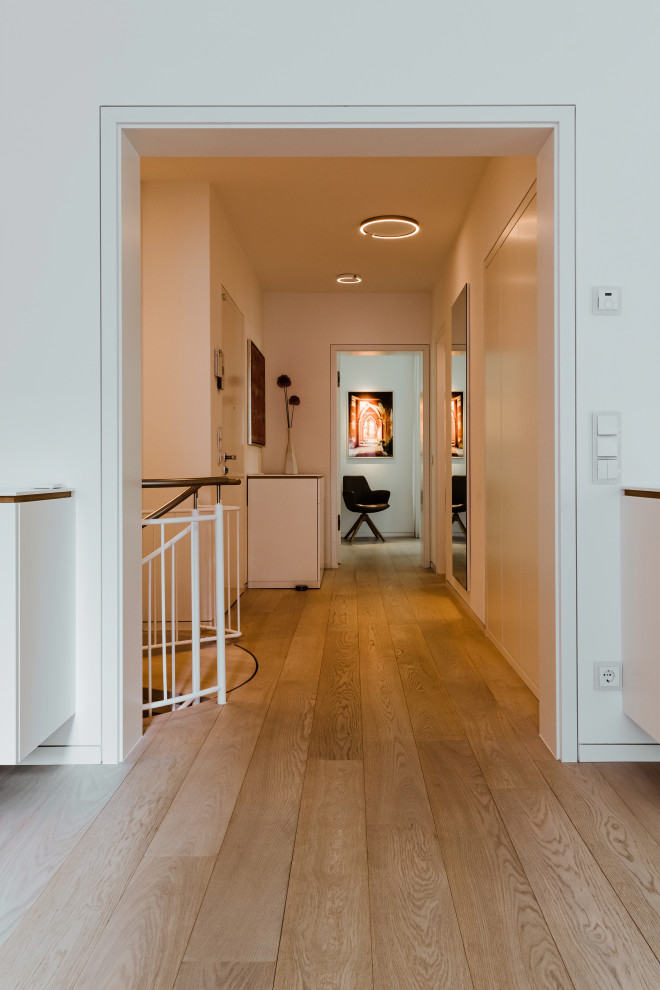 Mittelgroßer Moderner Flur mit weißer Wandfarbe, hellem Holzboden und weißem Boden in Berlin