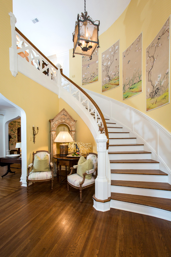 This is an example of a traditional wood curved staircase in Other with painted wood risers.