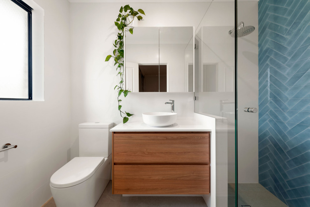 Photo of a contemporary bathroom in Other with flat-panel cabinets, medium wood cabinets, an alcove shower, blue tile, white walls, a vessel sink, grey floor, white benchtops, a single vanity and a floating vanity.