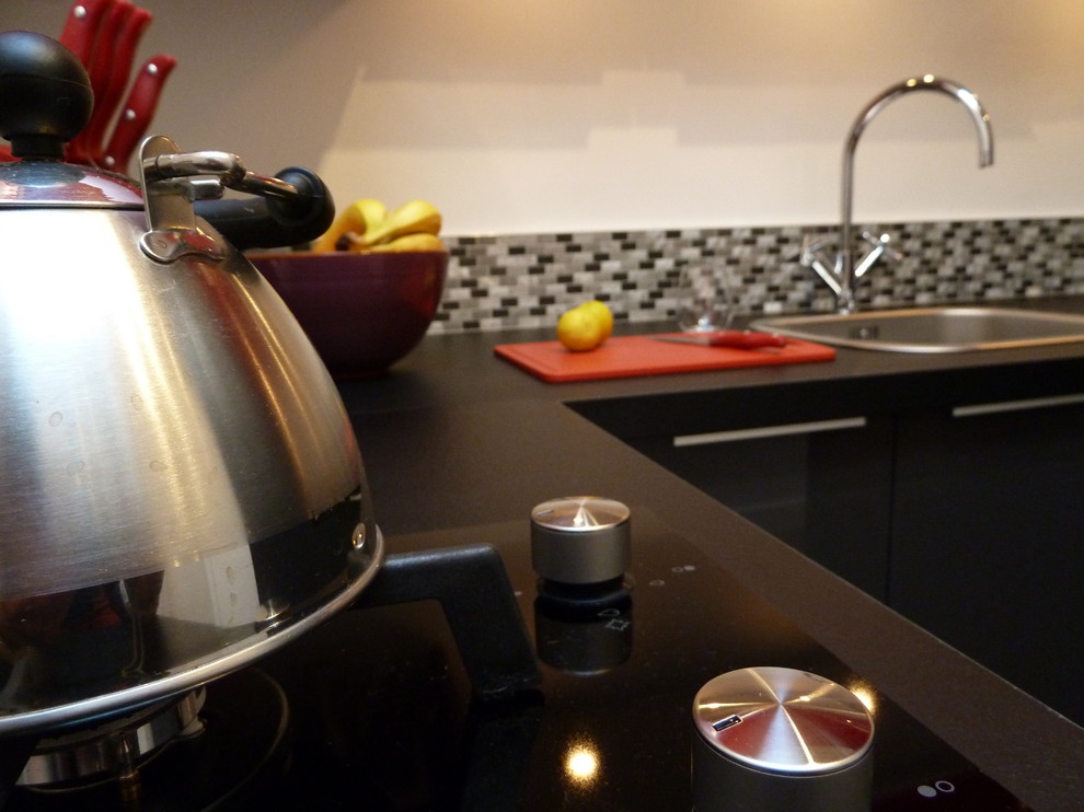 Cette photo montre cuisine in U With un évier encastré, des portes de placard rouges, un plan de travail en stratifié, une crédence grise and une crédence en carreau de verre.