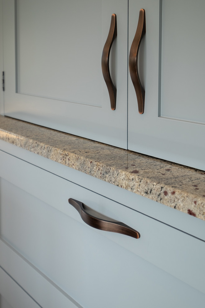 Inspiration for a mid-sized contemporary l-shaped separate kitchen in Hampshire with a farmhouse sink, shaker cabinets, blue cabinets, granite benchtops, multi-coloured splashback, stone slab splashback, black appliances, limestone floors, multi-coloured floor and multi-coloured benchtop.