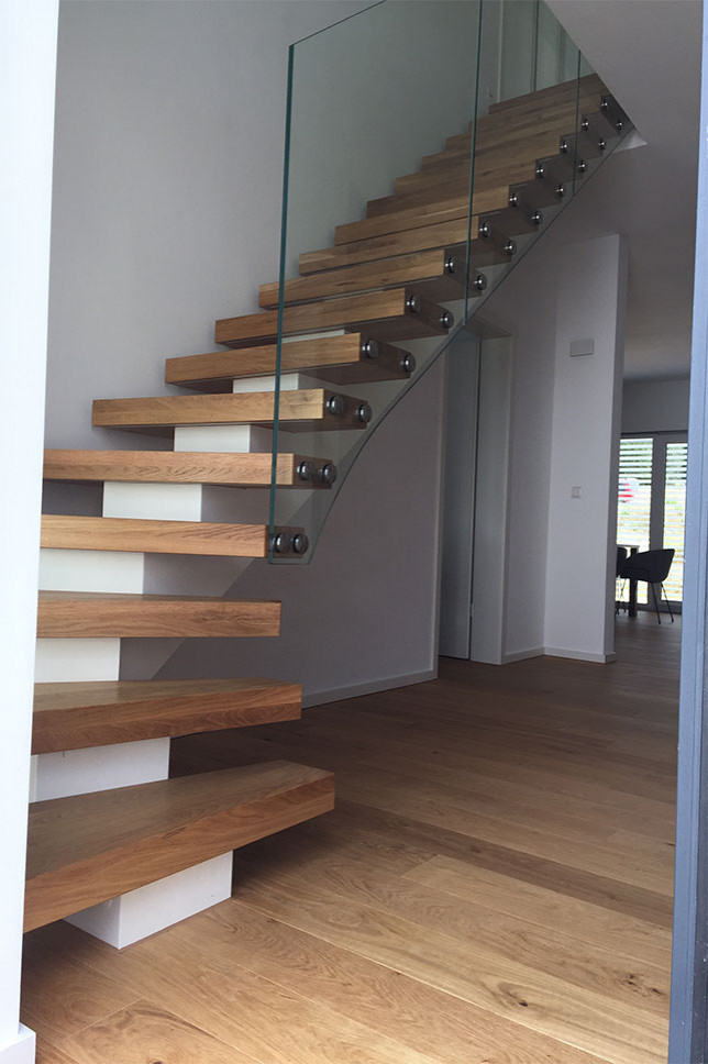Ejemplo de escalera curva escandinava con escalones de madera y barandilla de vidrio