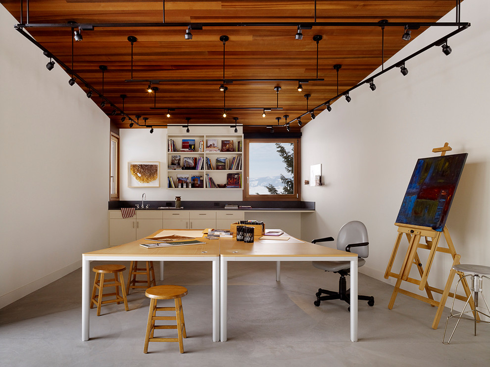 Photo of a contemporary home office in Other with concrete floors, white walls and grey floor.